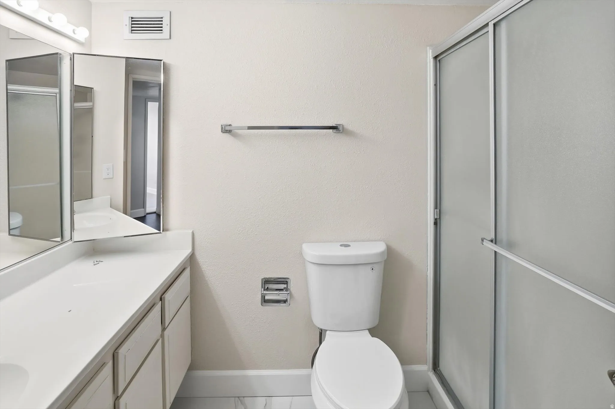Full bath with a stall shower, vanity, and a textured wall