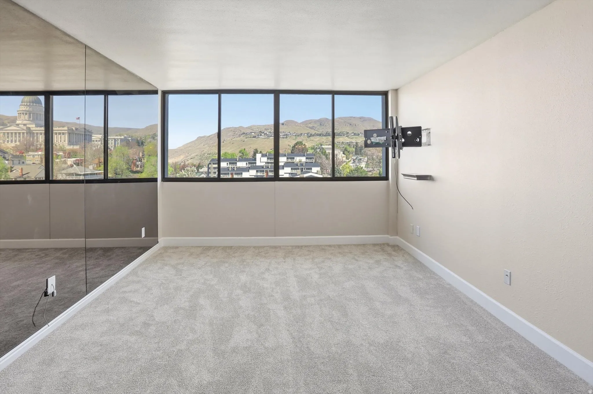 Empty room with a mountain view and light colored carpet