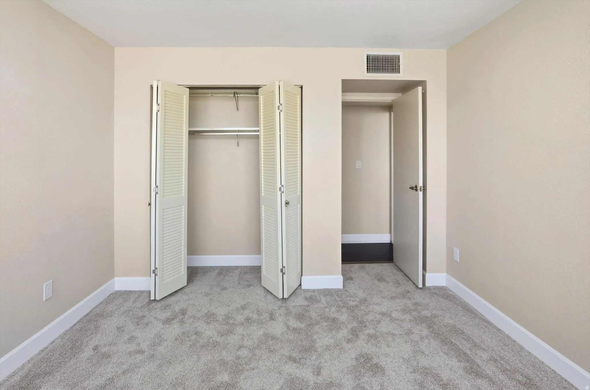 Unfurnished bedroom with light colored carpet and a closet
