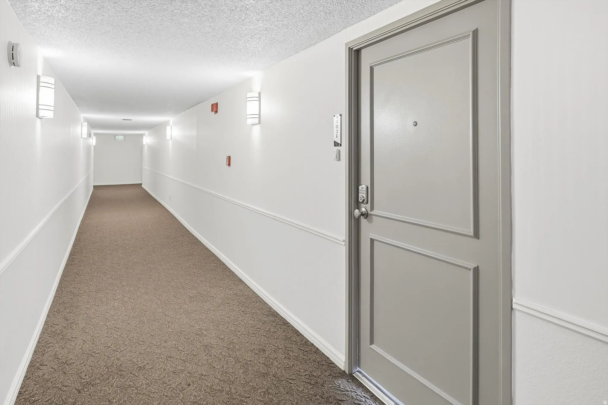 Hallway with dark carpet and a textured ceiling