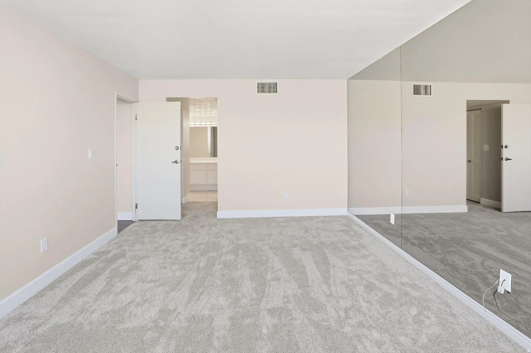 Unfurnished bedroom featuring light colored carpet and connected bathroom