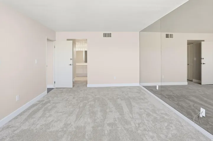 Unfurnished bedroom featuring light colored carpet and connected bathroom