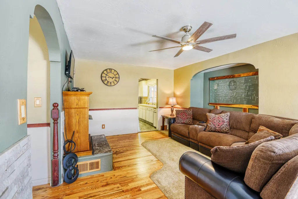 Living room featuring arched walkways, wood finished floors, and ceiling fan