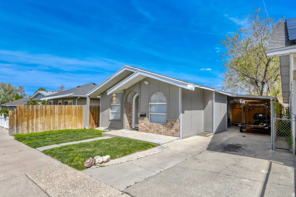Ranch-style house with concrete driveway, stone siding, and an attached carport