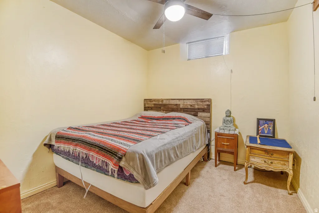 Bedroom featuring a textured wall, a ceiling fan, and light carpet