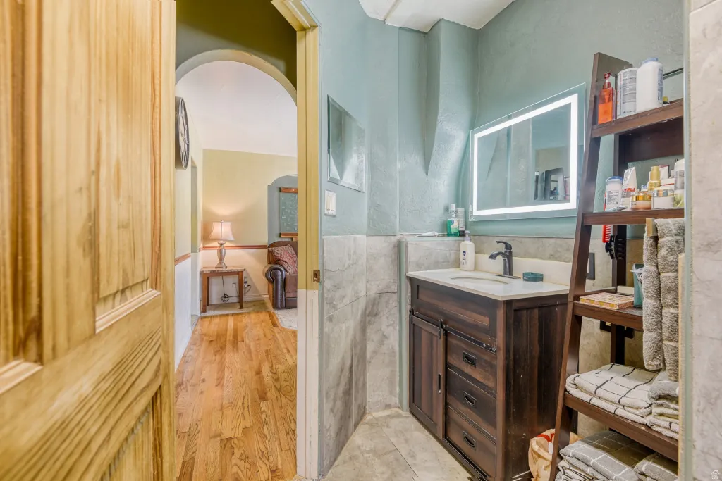 Bathroom with vanity, light wood finished floors, tile walls, and a wainscoted wall