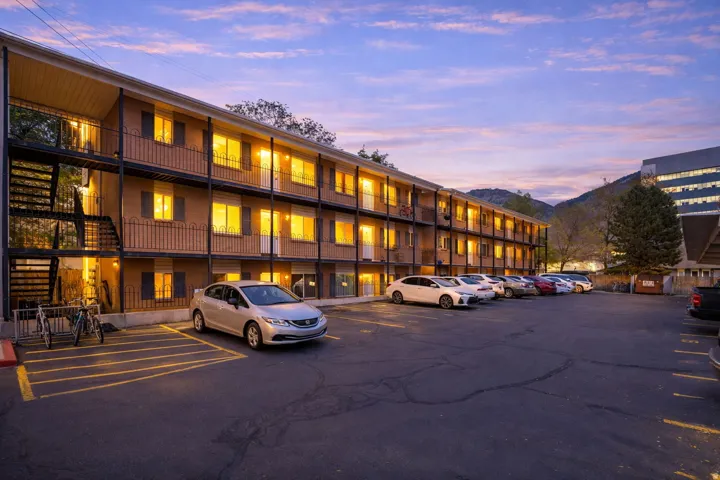 Property at dusk featuring uncovered parking and a view of apartment building / complex
