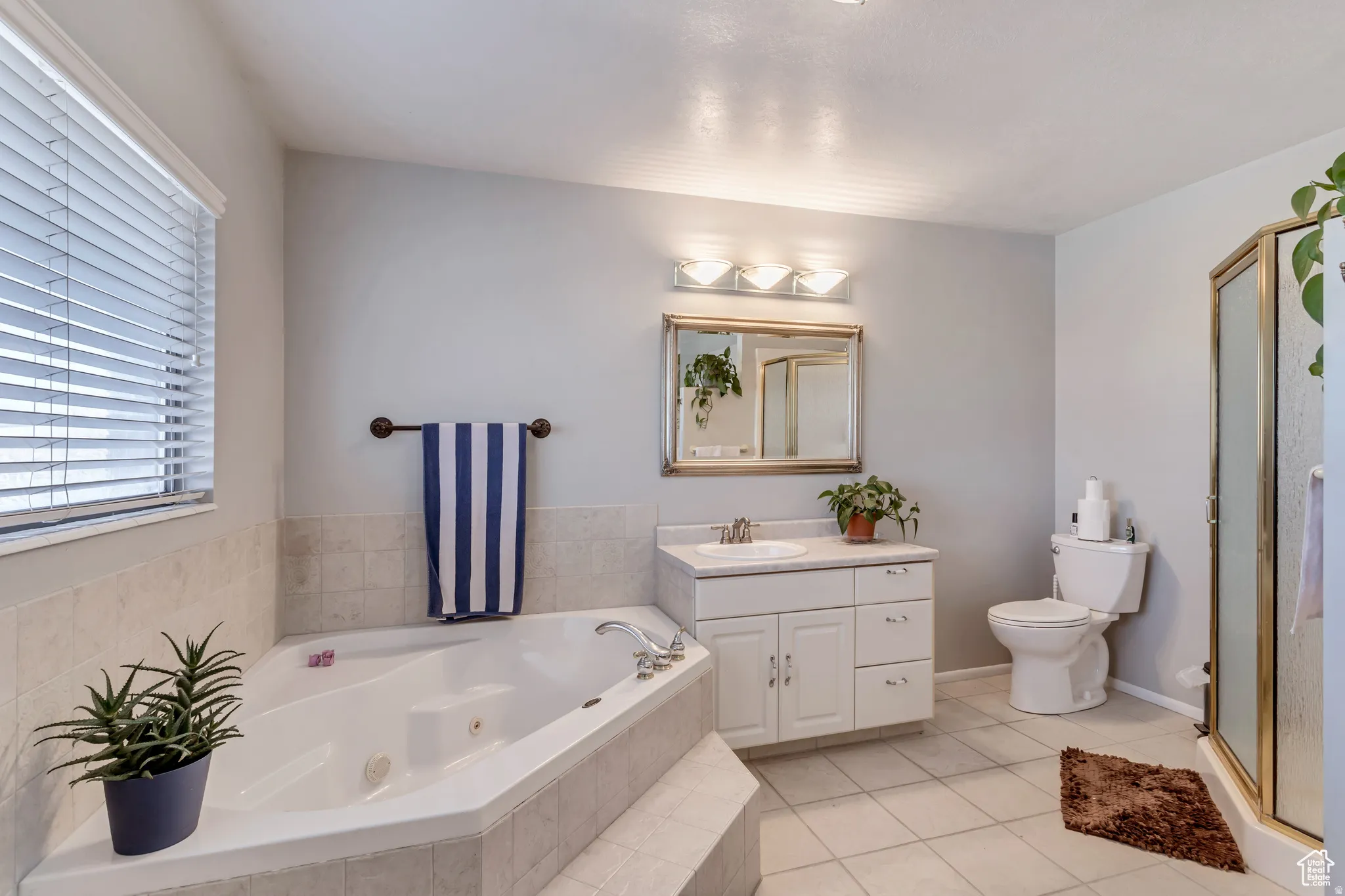 Full bath featuring vanity, a stall shower, a tub with jets, and light tile patterned floors
