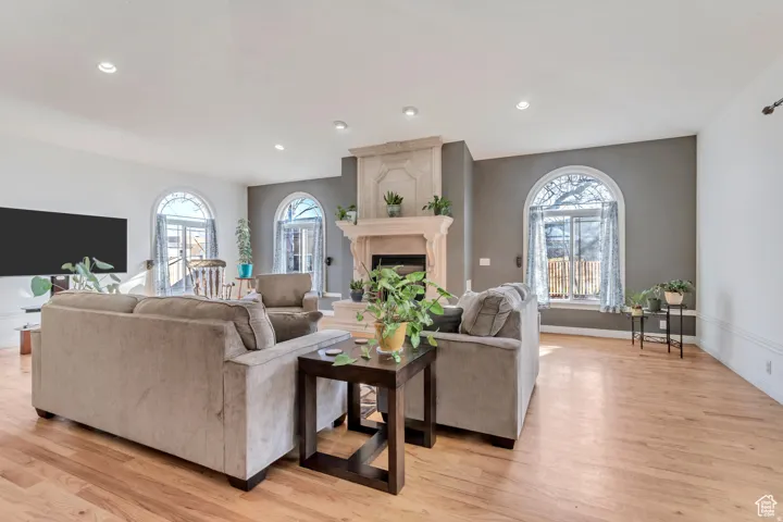 Hardwood flooring, recessed lighting, arched windows, and a decorative fireplace create a refined living space