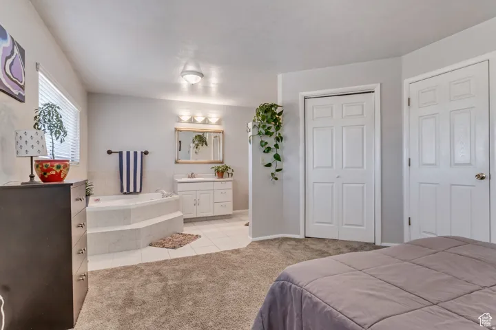 Built-in jetted tub with tiled surround, single vanity with integrated sink, panel doors, and neutral wall paint