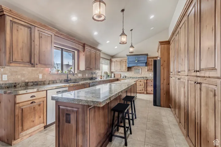 Kitchen featuring extensive wood cabinetry, stone countertops, a tile backsplash, and recessed lighting
