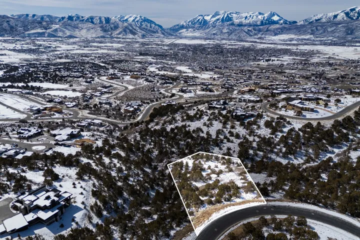 Snowy aerial view with a mountain view and property parcel outlined