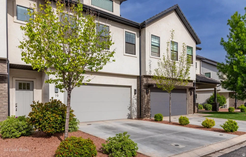 View of front of house with a garage, concrete driveway, stucco siding, and brick siding