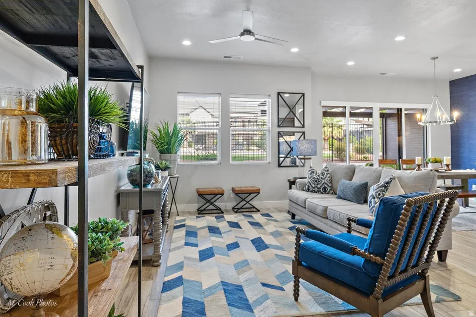 Living room featuring suspended lighting, ceiling fan, and light wood-type flooring