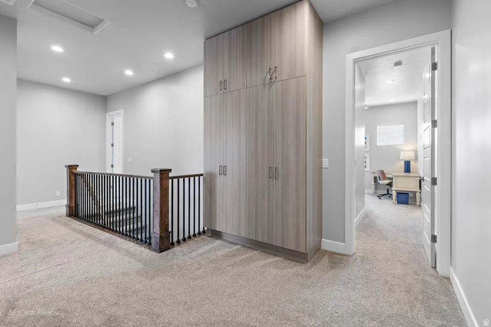 Corridor with light colored carpet and recessed lighting