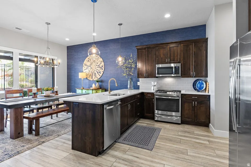 Kitchen featuring a peninsula, dark wood finish cabinets, stainless steel appliances, and light wood finished floors