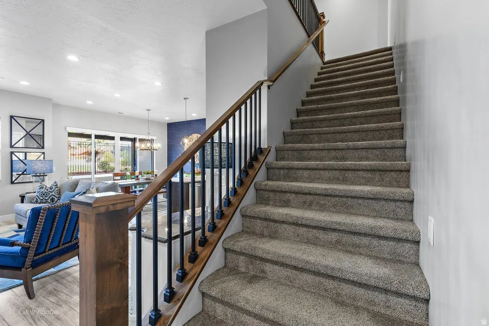 Stairs with hanging lights, wood finished floors, and a textured ceiling