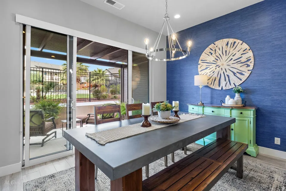 Dining room with light wood finished floors, suspended lighting, wallpapered walls, and an accent wall