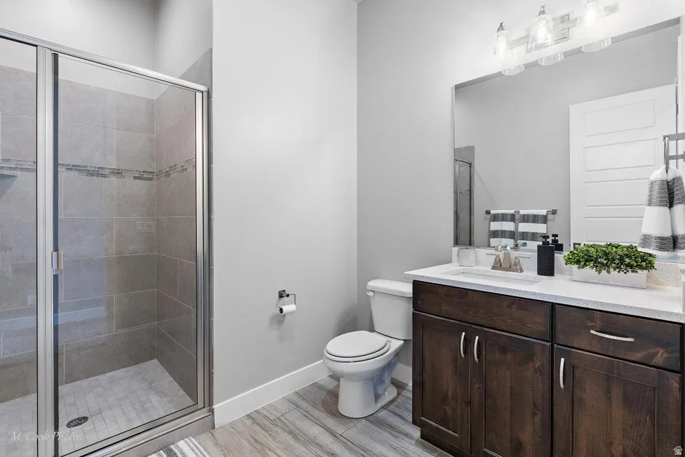 Full bath featuring vanity, a shower stall, and light wood finished floors