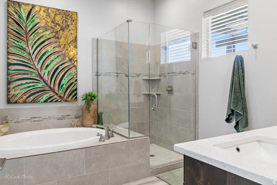 Bathroom with vanity, a bath, and a stall shower