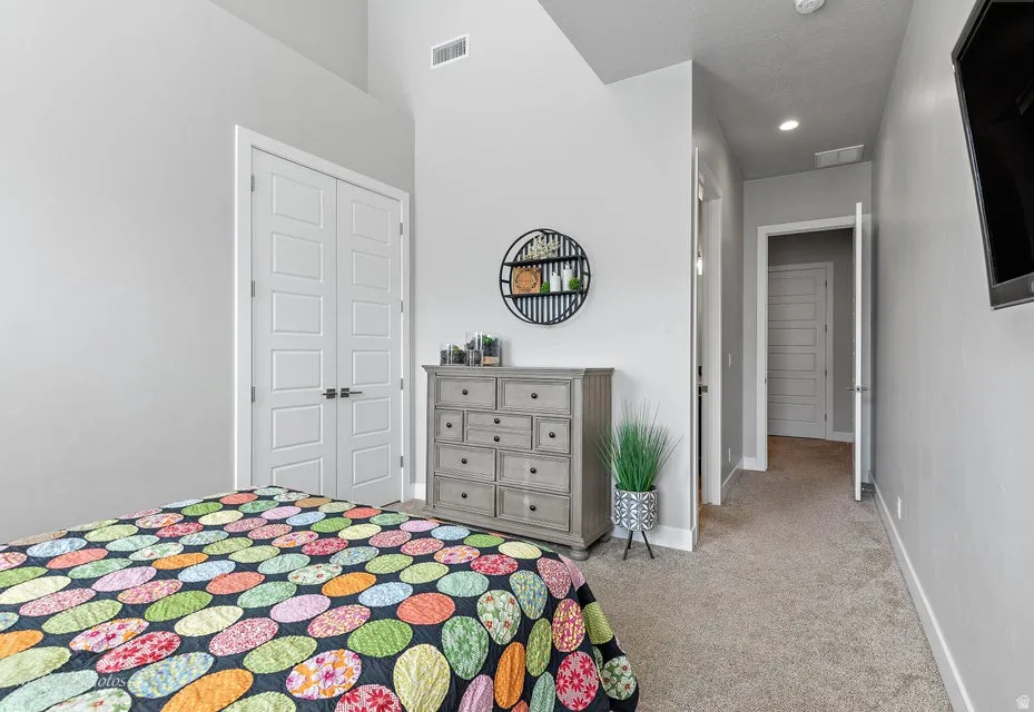 Bedroom with light colored carpet and a closet