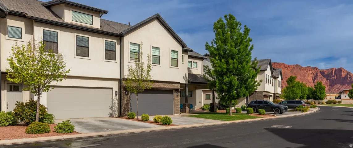 View of front of property featuring a residential view, stucco siding, an attached garage, concrete driveway, and a mountain view