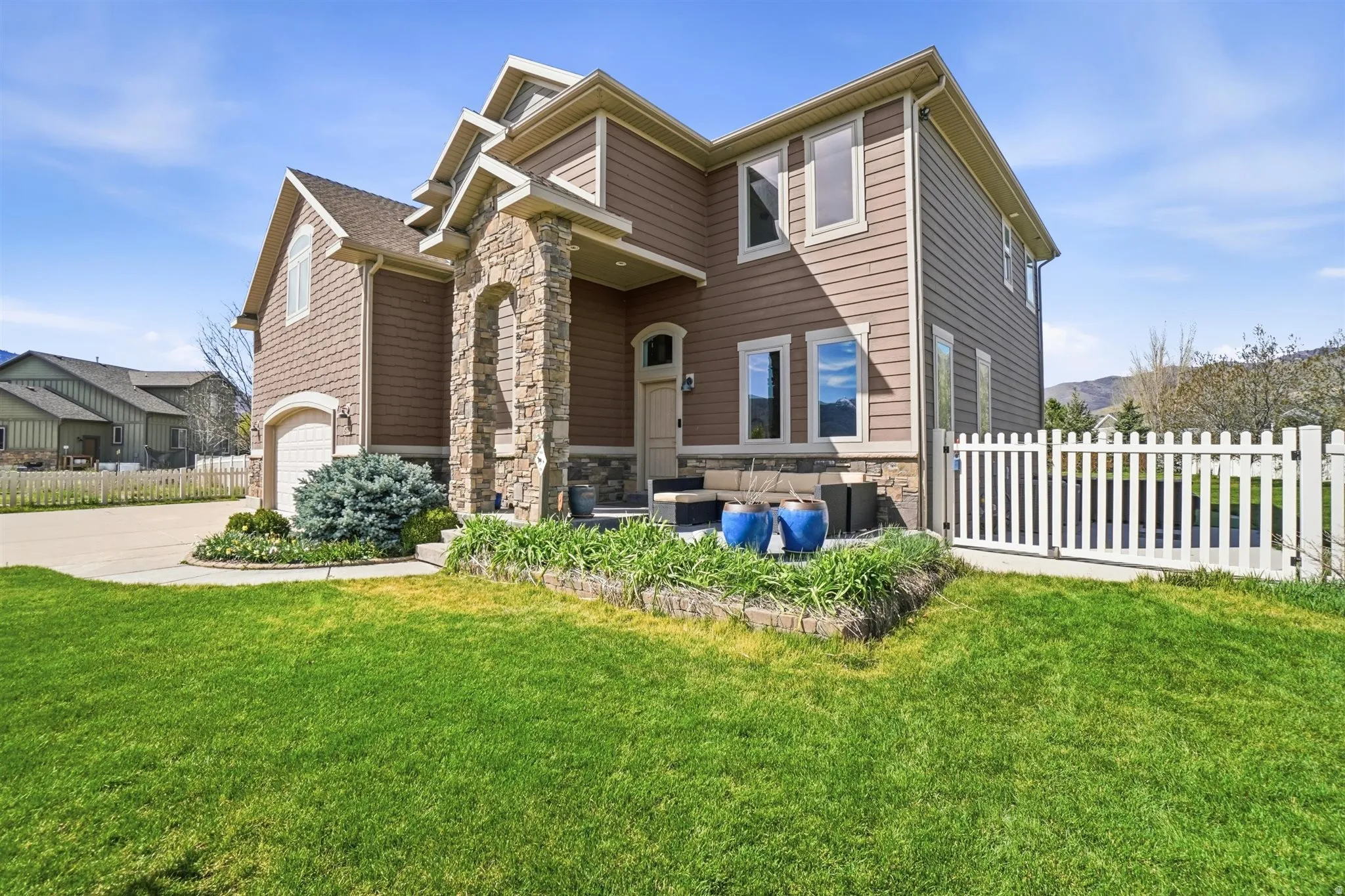 View of front of home featuring stone siding, an outdoor lounge area, a garage, and concrete driveway