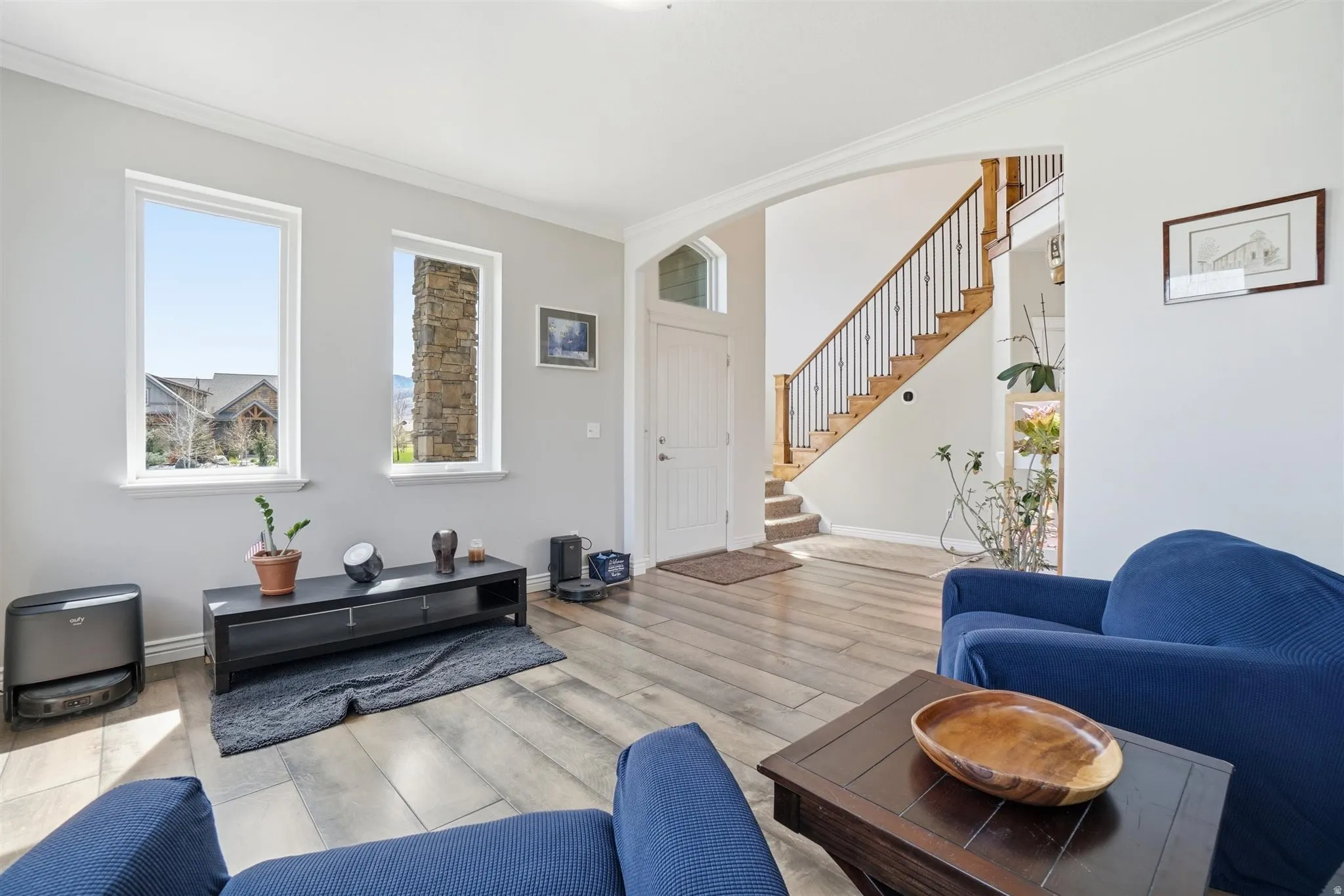 Living area with crown molding, light wood-style flooring, and arched walkways