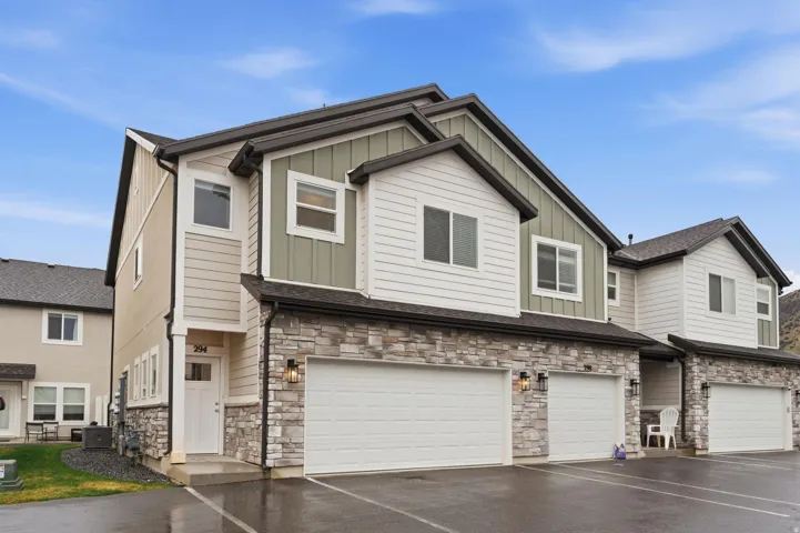 Craftsman-style home with stone siding, board and batten siding, an attached garage, and driveway