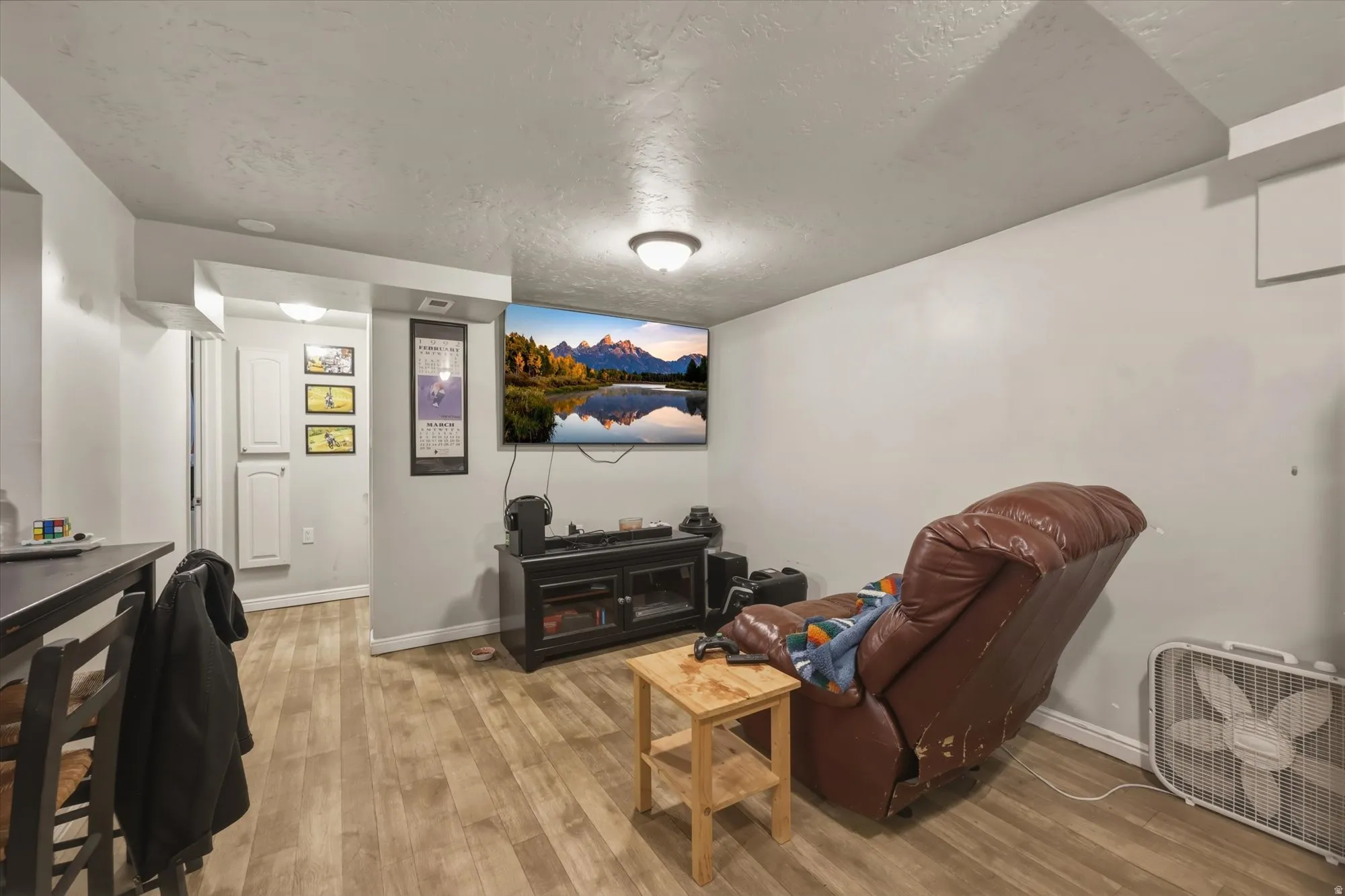 Living area with light wood-style floors and a textured ceiling