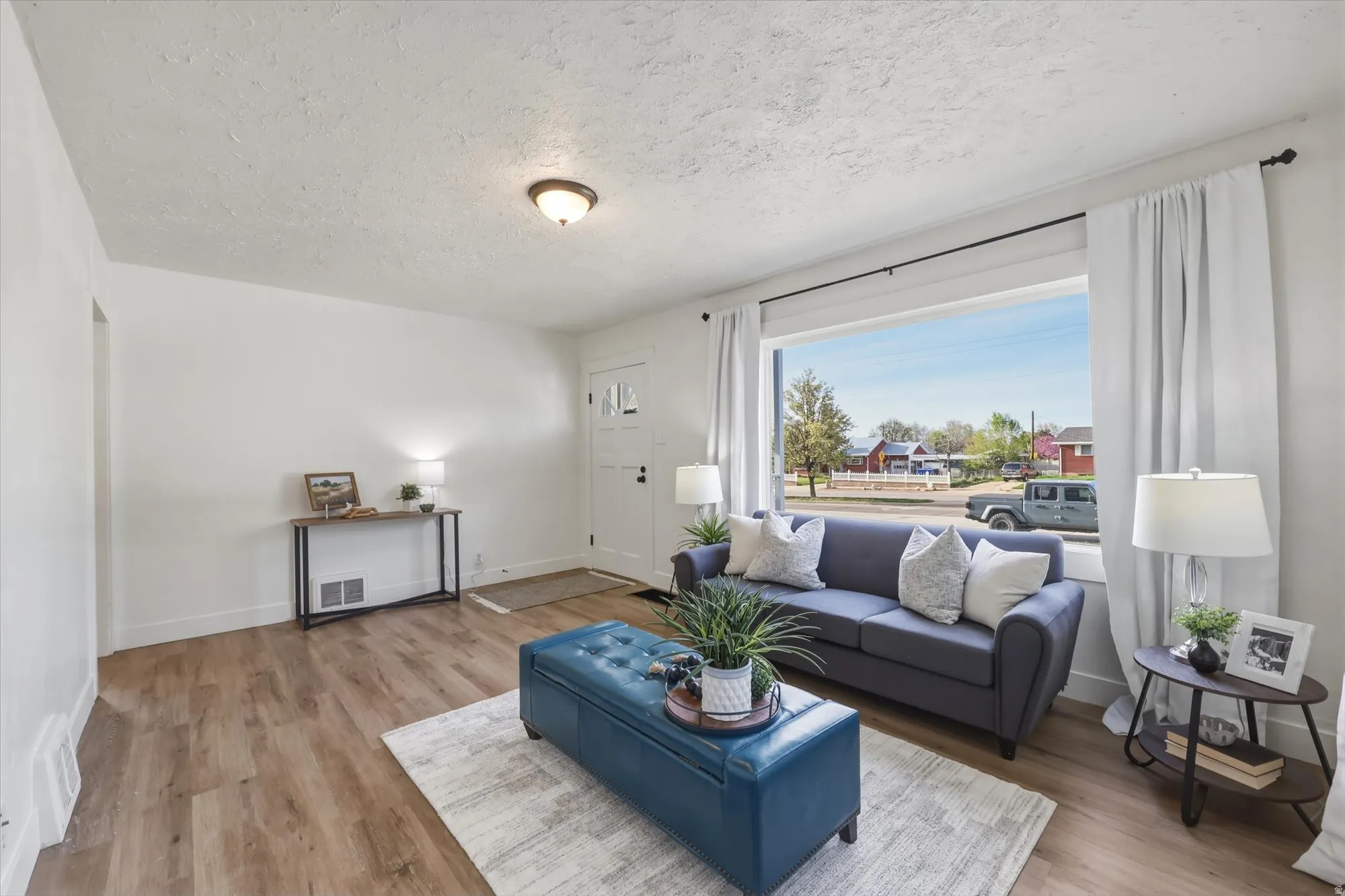 Living room featuring light wood-style flooring and a textured ceiling