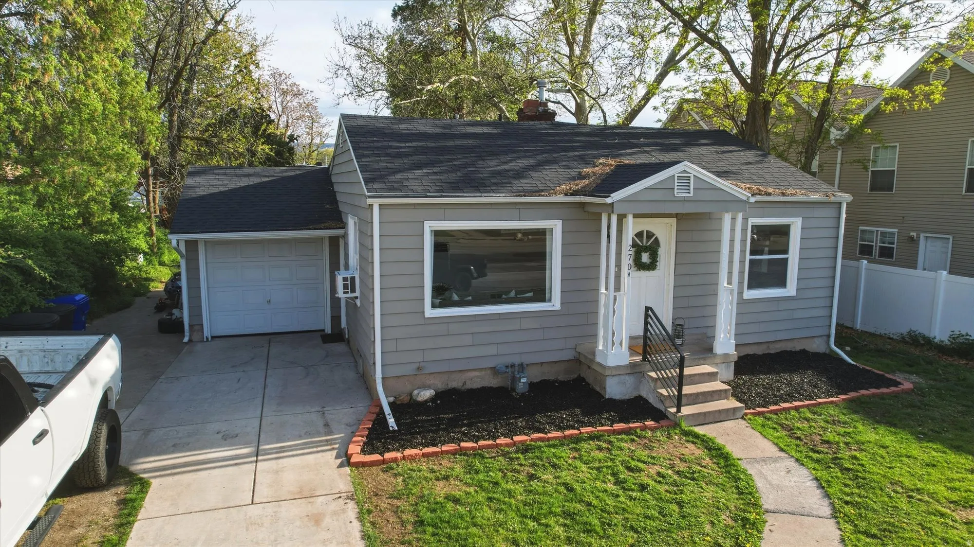 Bungalow-style home featuring a garage, driveway, a shingled roof, and a chimney