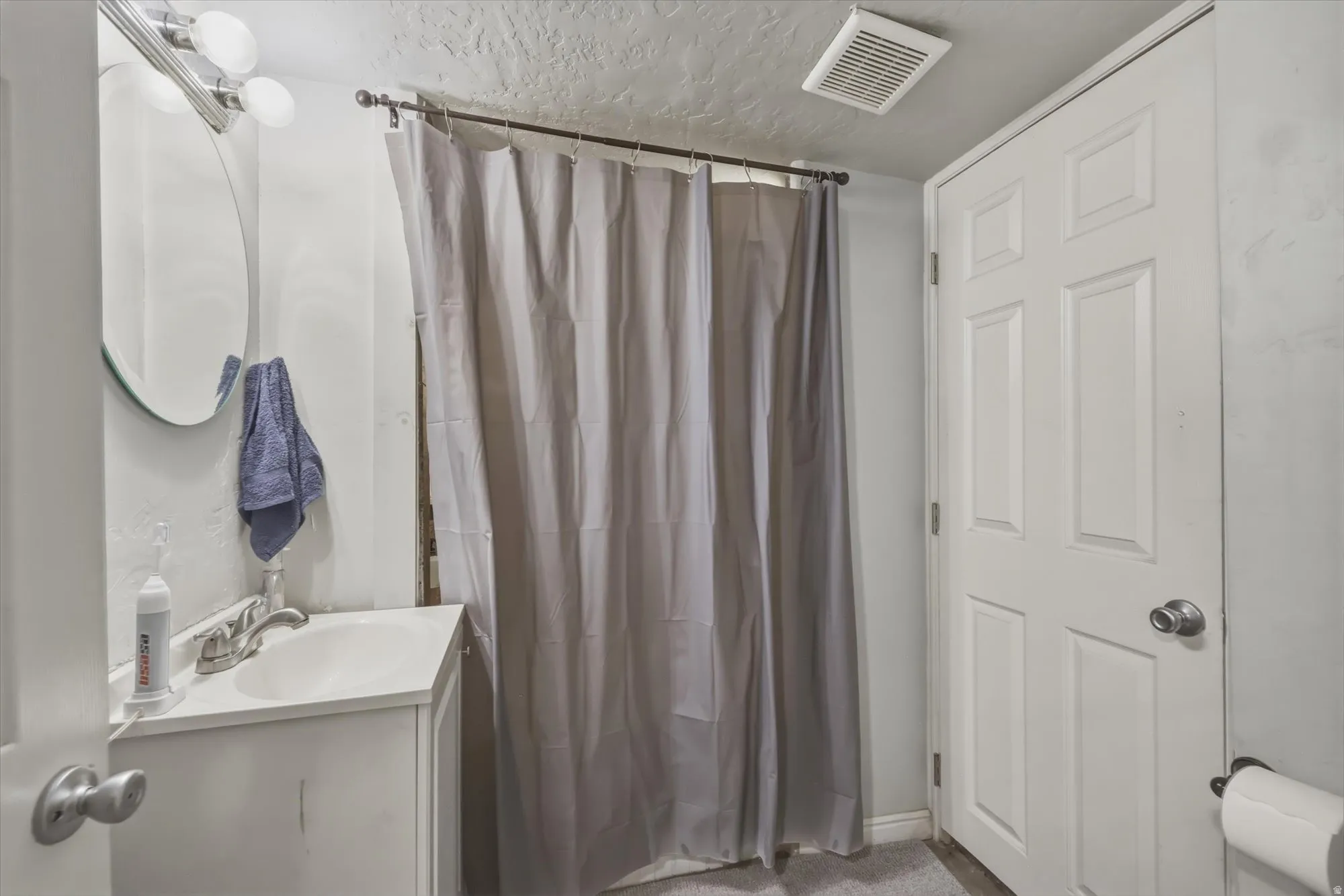 Bathroom featuring a shower with curtain, vanity, and a textured ceiling