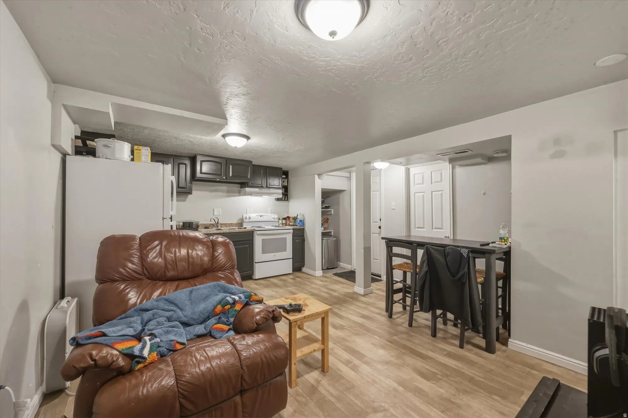 Kitchen featuring a textured ceiling, light wood-style flooring, white appliances, and light countertops