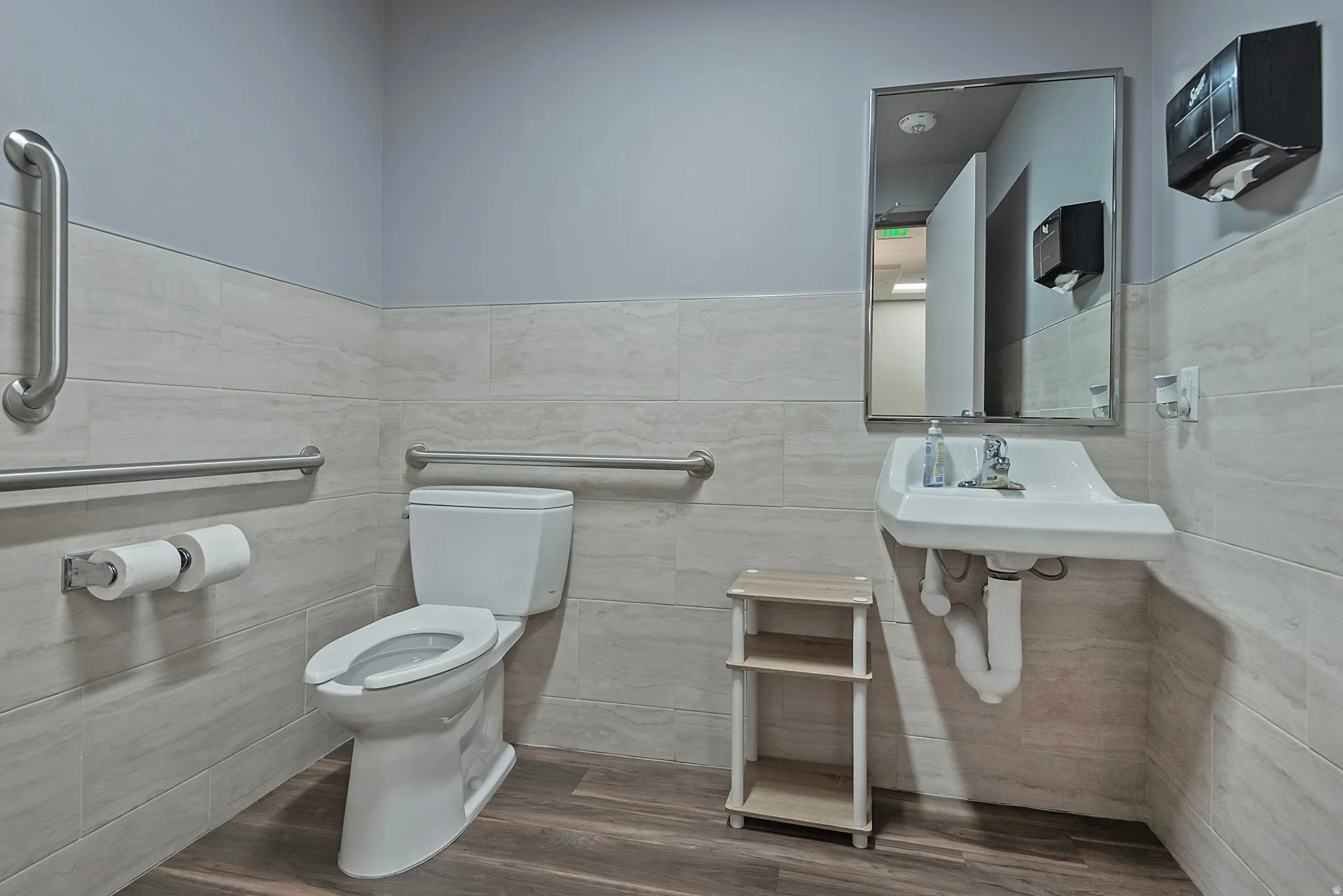 Bathroom featuring dark wood-style floors, tile walls, and a wainscoted wall