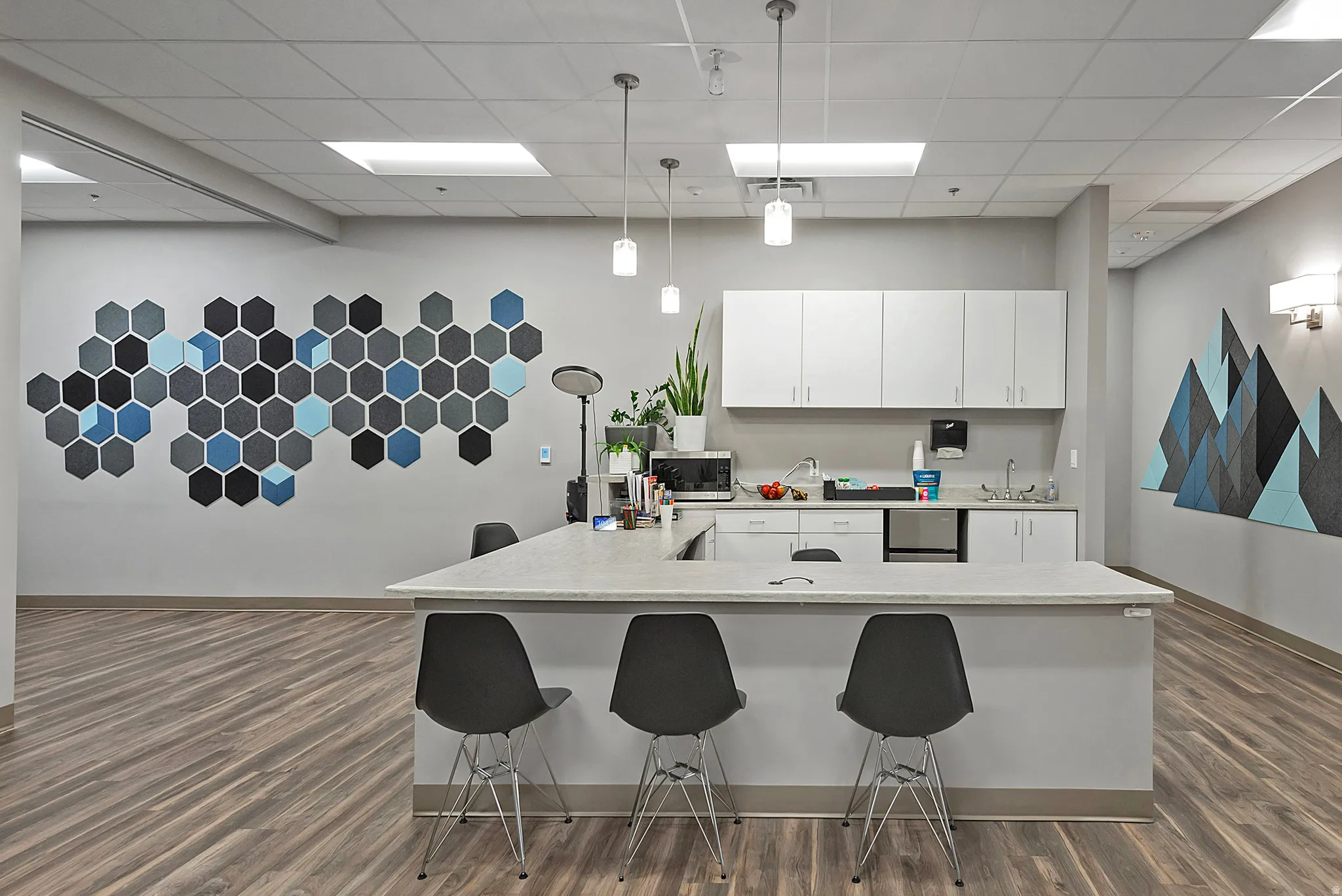 Kitchen with decorative light fixtures, a breakfast bar, a paneled ceiling, white cabinetry, and stainless steel microwave