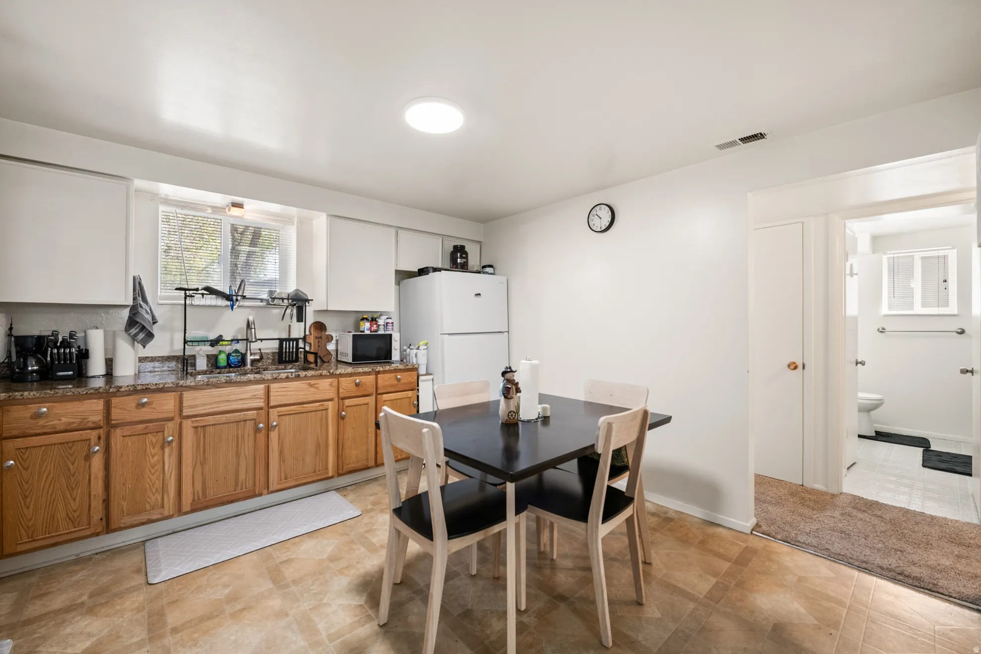 Kitchen with wood finish cabinetry, white appliances, and dark stone counters