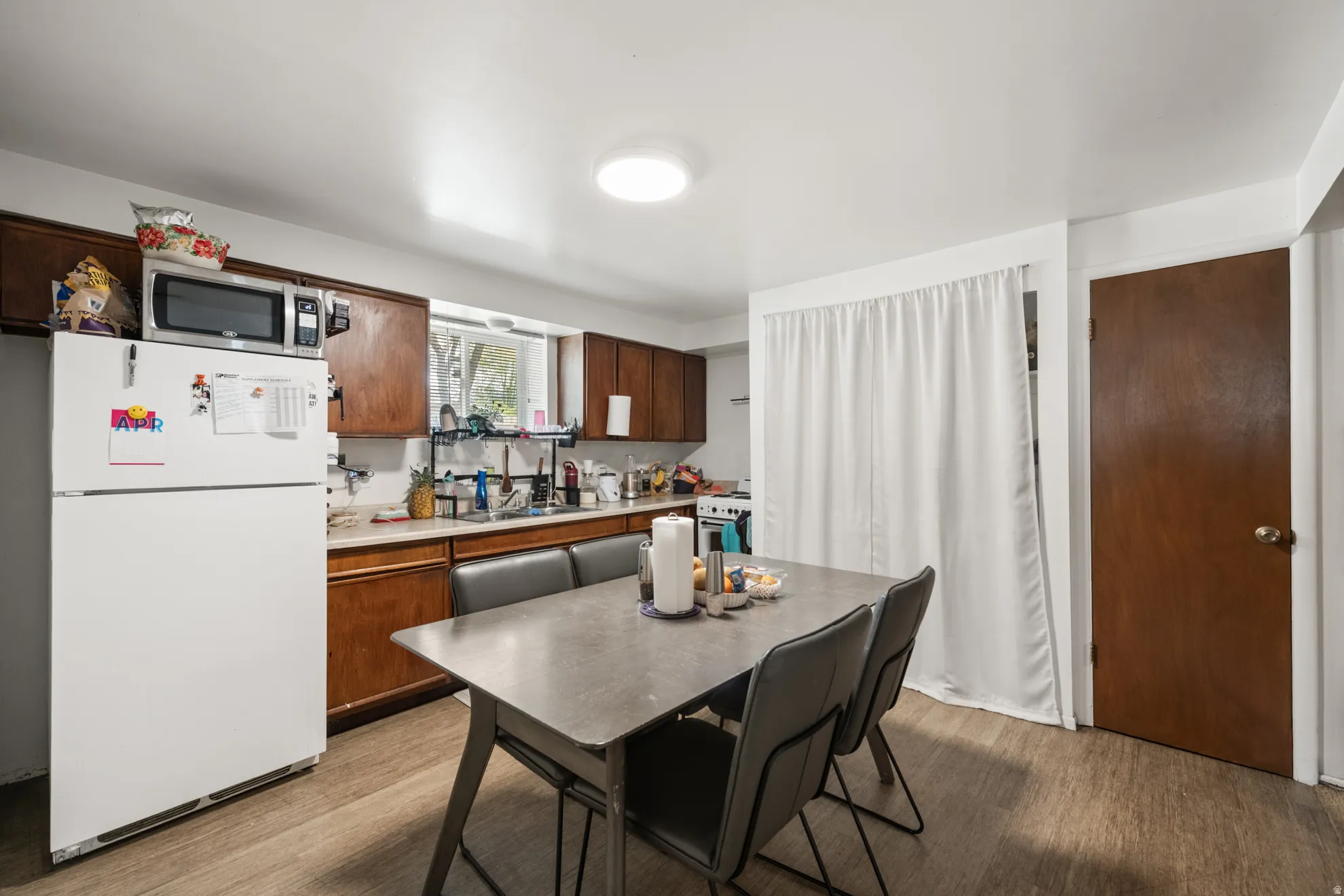 Kitchen featuring white appliances, light countertops, and light wood-style flooring