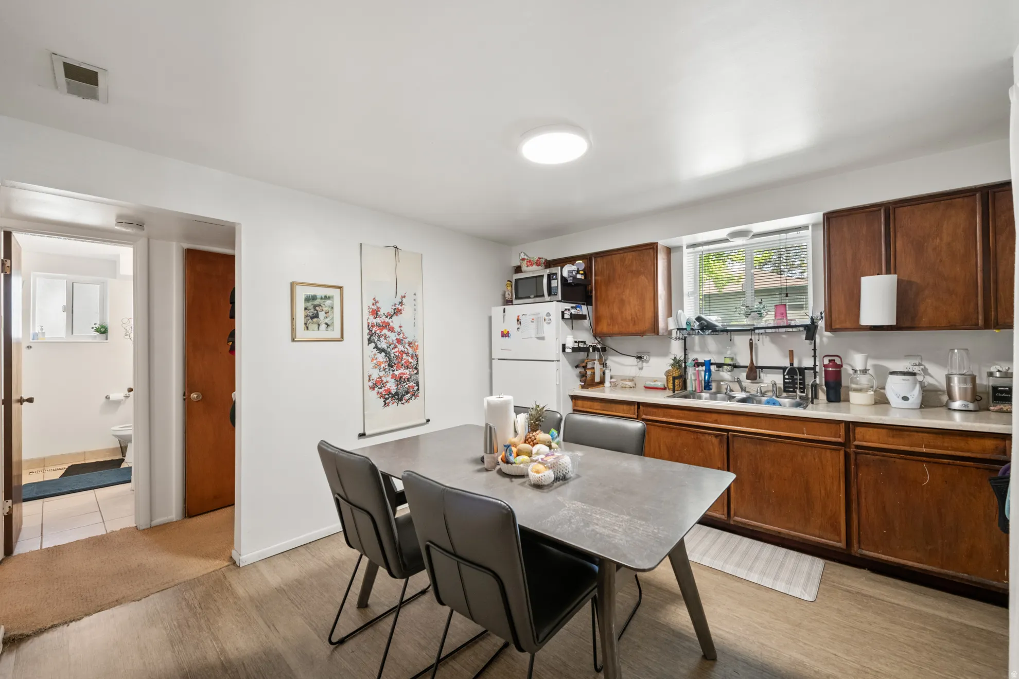 Kitchen featuring light countertops, light wood finished floors, freestanding refrigerator, and wood finish cabinetry