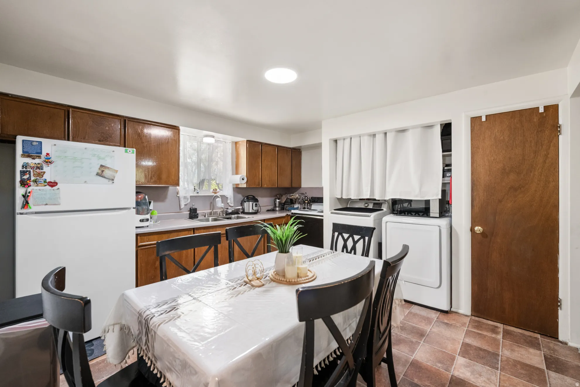 Kitchen featuring light countertops, freestanding refrigerator, stone finish floors, and washer and clothes dryer