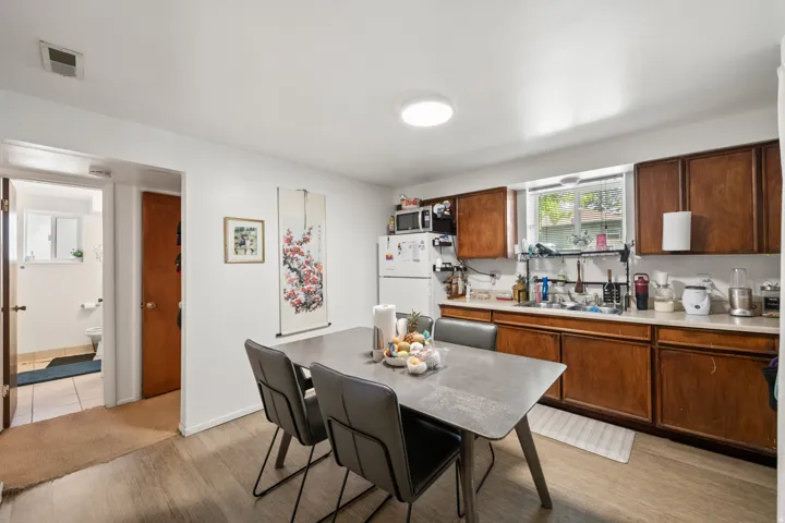 Kitchen featuring light countertops, light wood finished floors, freestanding refrigerator, and wood finish cabinetry