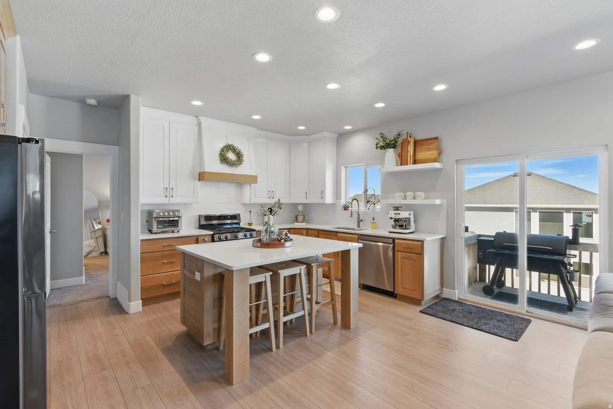 Kitchen featuring stainless steel appliances, a center island, open shelves, light wood finished floors, and recessed lighting
