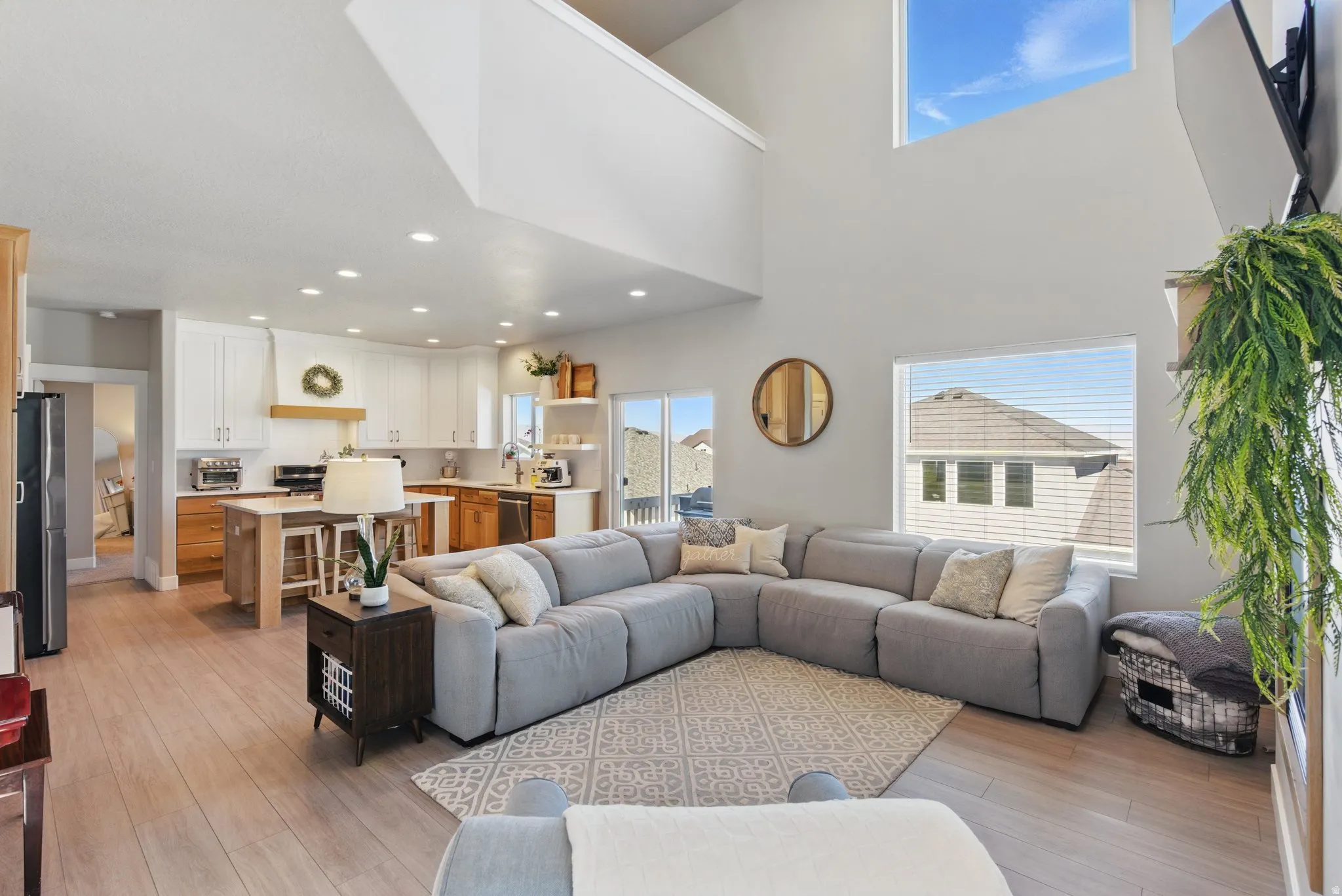 Living room featuring light wood finished floors, recessed lighting, and a high ceiling