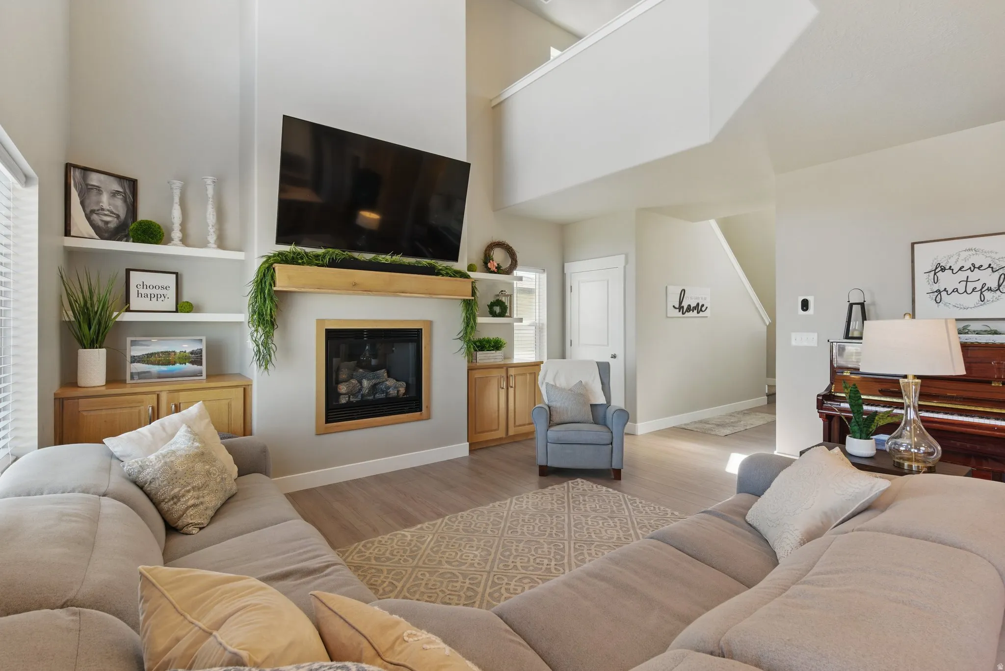 Living room with wood finished floors, a glass covered fireplace, and a high ceiling