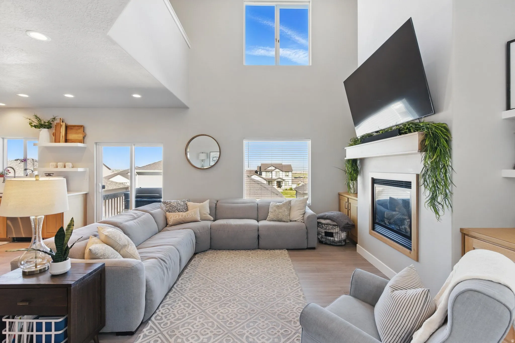Living room with a glass covered fireplace, light wood-type flooring, a high textured ceiling, and recessed lighting