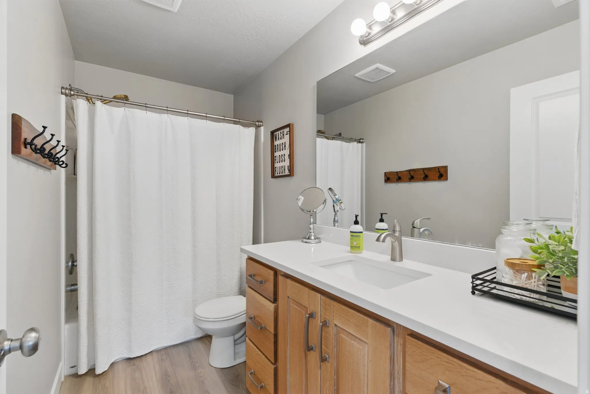 Full bathroom featuring vanity, light wood finished floors, and shower / bath combination with curtain