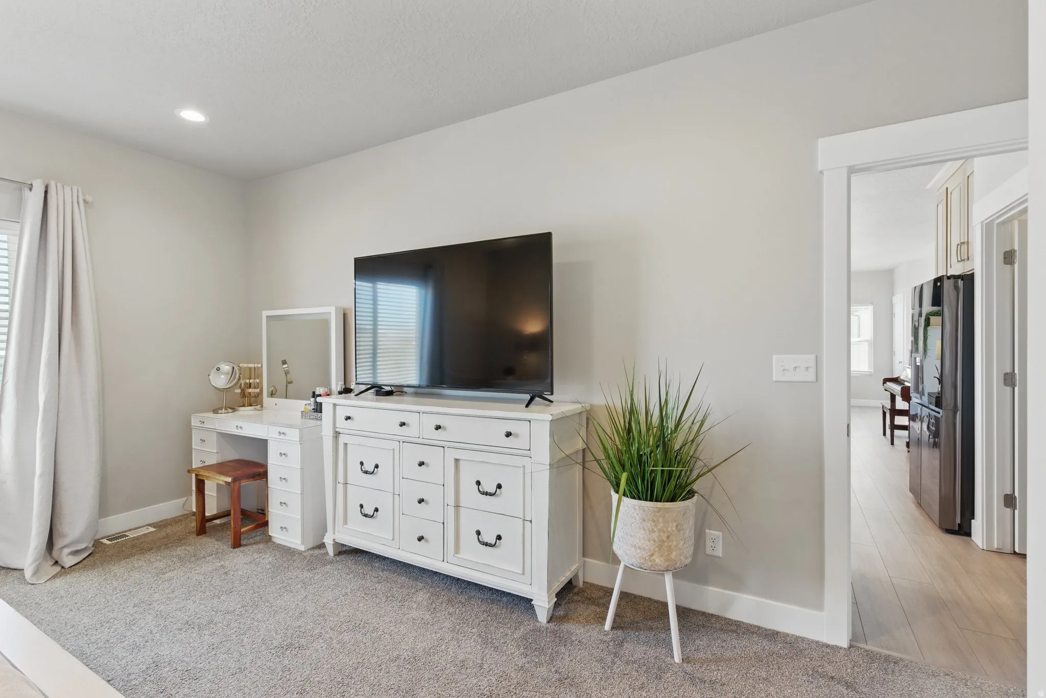 Bedroom featuring multiple windows, light carpet, freestanding refrigerator, and recessed lighting