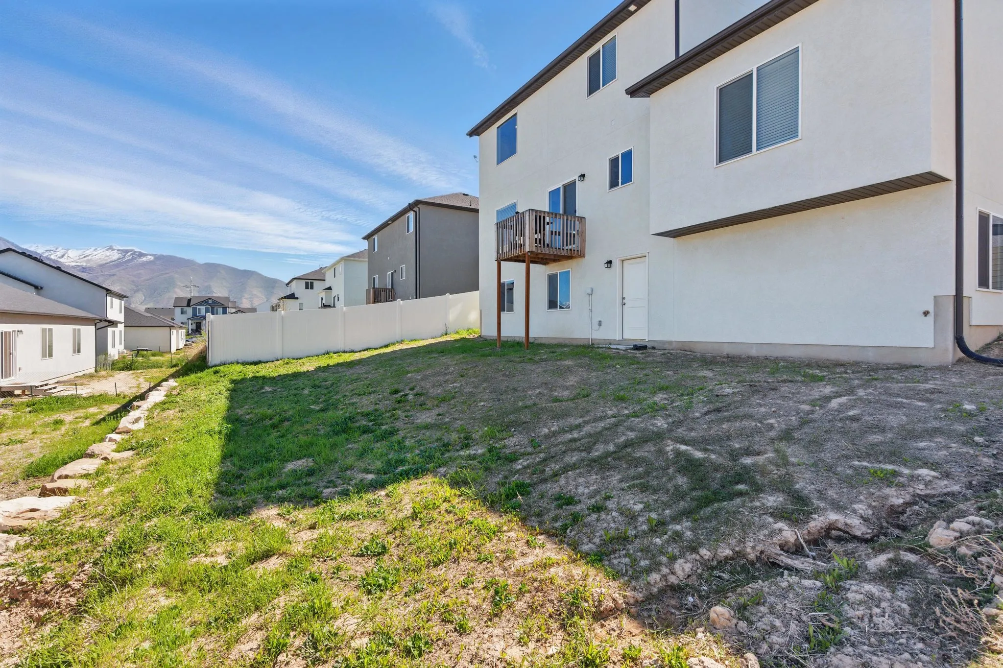 Rear view of house featuring a mountain view, stucco siding, a residential view, and a balcony