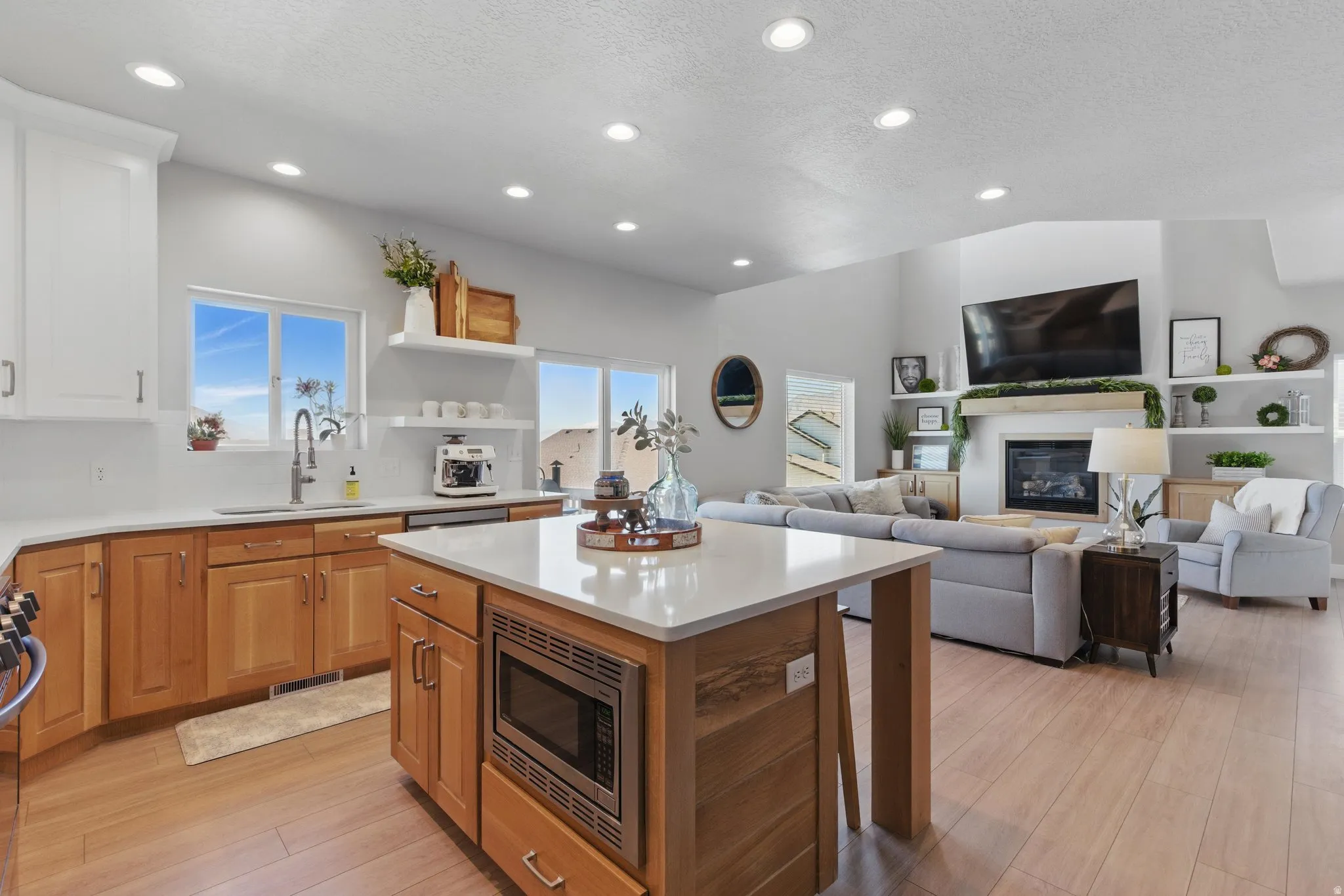 Kitchen featuring a glass covered fireplace, stainless steel appliances, light wood-style floors, open floor plan, and recessed lighting