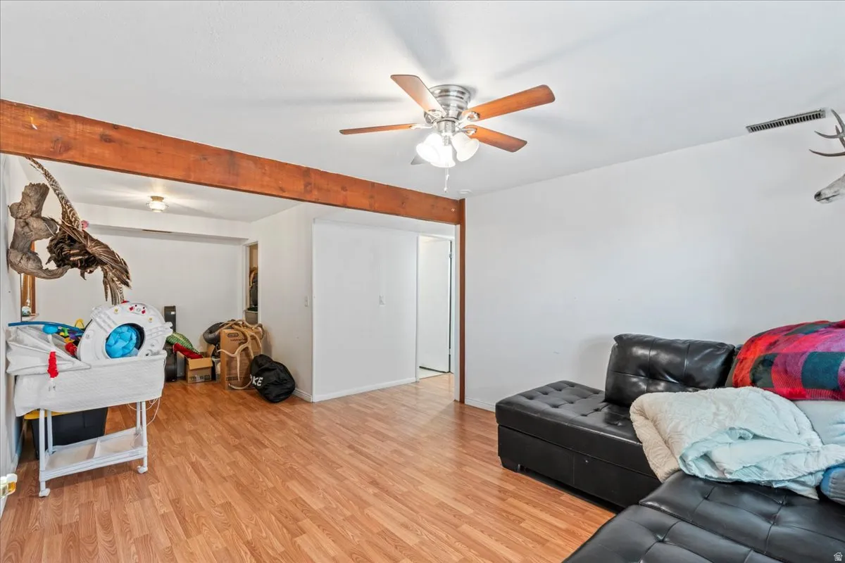Living room with light wood-type flooring and a ceiling fan